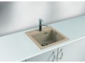 Fregadero de granito beige con grifo de cocina cromado sobre una superficie de trabajo blanca
