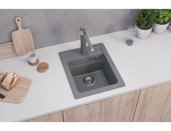 Fregadero de cocina de granito gris con grifo a juego sobre una superficie de cocina blanca
