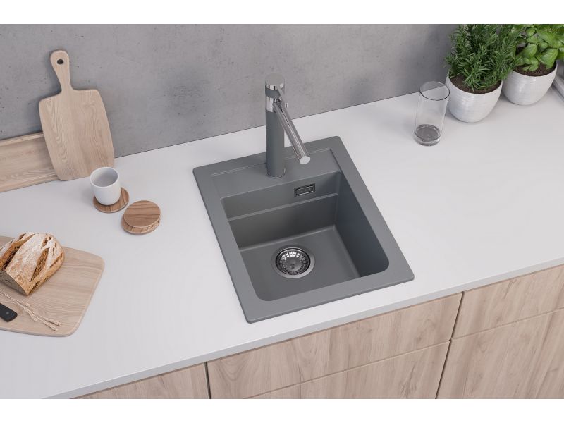 Fregadero de cocina de granito gris con grifo a juego sobre una superficie de cocina blanca