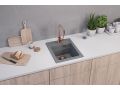 Fregadero de granito gris empotrado en una encimera de cocina blanca, con un grifo de cocina de cobre y un desagüe de cobre