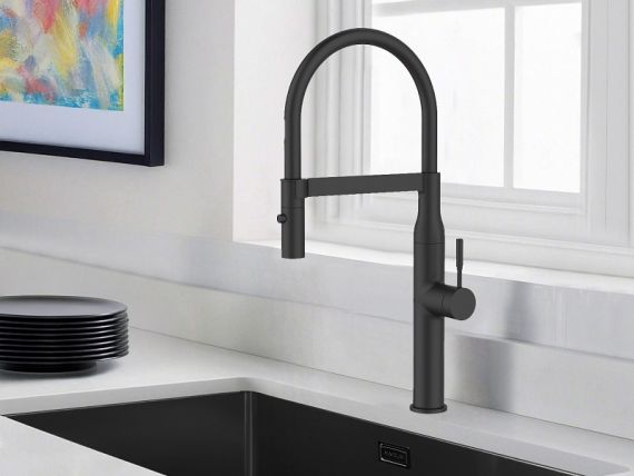 Grifo de cocina blanco y fregadero de acero inoxidable en una cocina blanca con un fondo verde o naturaleza visible a través de la ventana