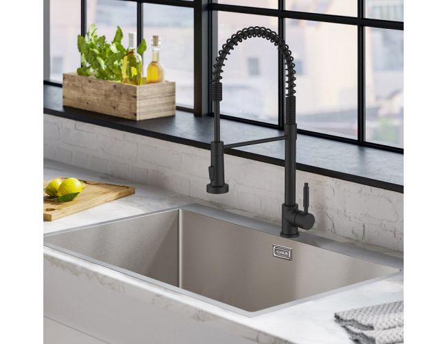 Elegant black kitchen faucet with a professional, industrial-style design, paired with a modern stainless steel sink in a bright kitchen setting, featuring a marble countertop and a window overlooking an urban landscape